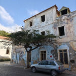 Stary kolonialny budynek, drzewo i zaparkowany samochód na jednej z ulic Mindelo