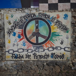 Mural z symbolem pokoju i napisem o jedności namalowany na kamiennym murze w Ponta do Sol