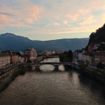Widok na rzekę Isère, most i zabudowę Grenoble o zachodzie słońca