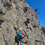Wspinacze na skalnym odcinku Via Ferrata des Lacs Robert w Chamrousse
