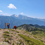 Turyści przy tablicy informacyjnej via ferraty Des 3 Fontaines w Chamrousse