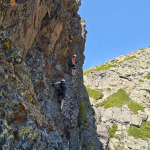 Uczestnicy pokonują skalny fragment via ferraty Des 3 Fontaines w Chamrousse