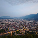 Szeroka panorama Grenoble o zmierzchu z górami i kolejką linową po prawej stronie