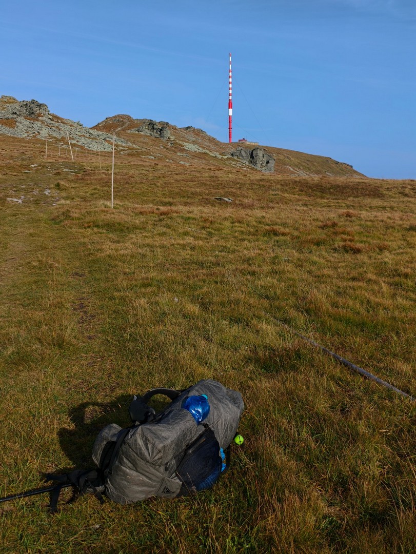 Plecak trekkingowy na trawie z widokiem na nadajnik na grzbiecie 