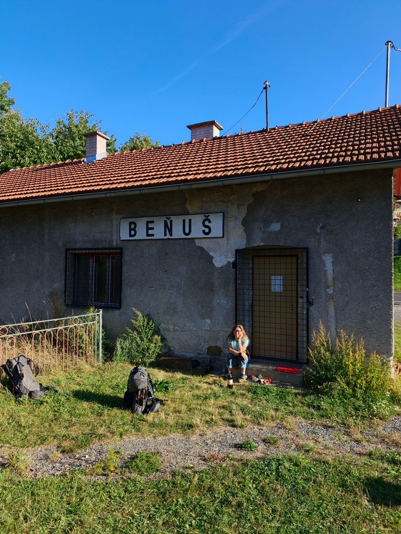 Budynek z napisem Beňuš, przy którym odpoczywa turystka z plecakami po zejściu ze szlaku