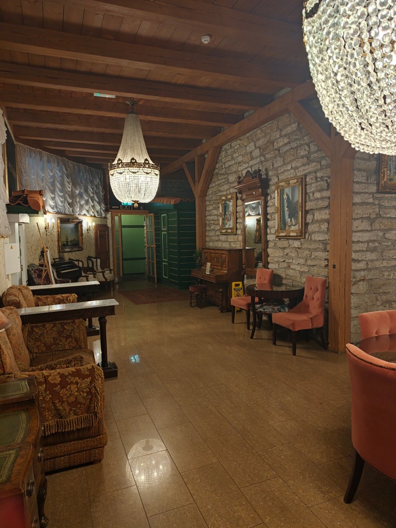 Salon hotelu St. Olav w Tallinnie z kamiennymi ścianami, zabytkowymi meblami i kryształowymi żyrandolami