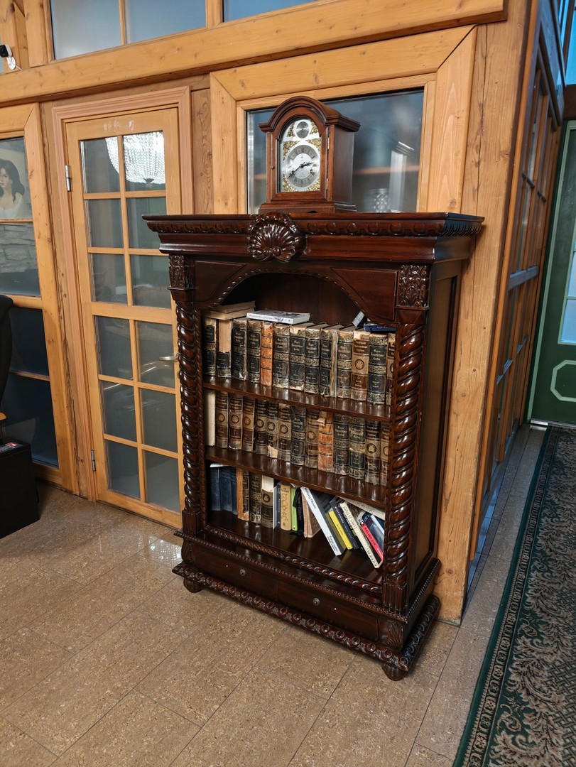 Drewniana biblioteczka ze starymi książkami i zabytkowym zegarem w hotelu St. Olav w Tallinnie