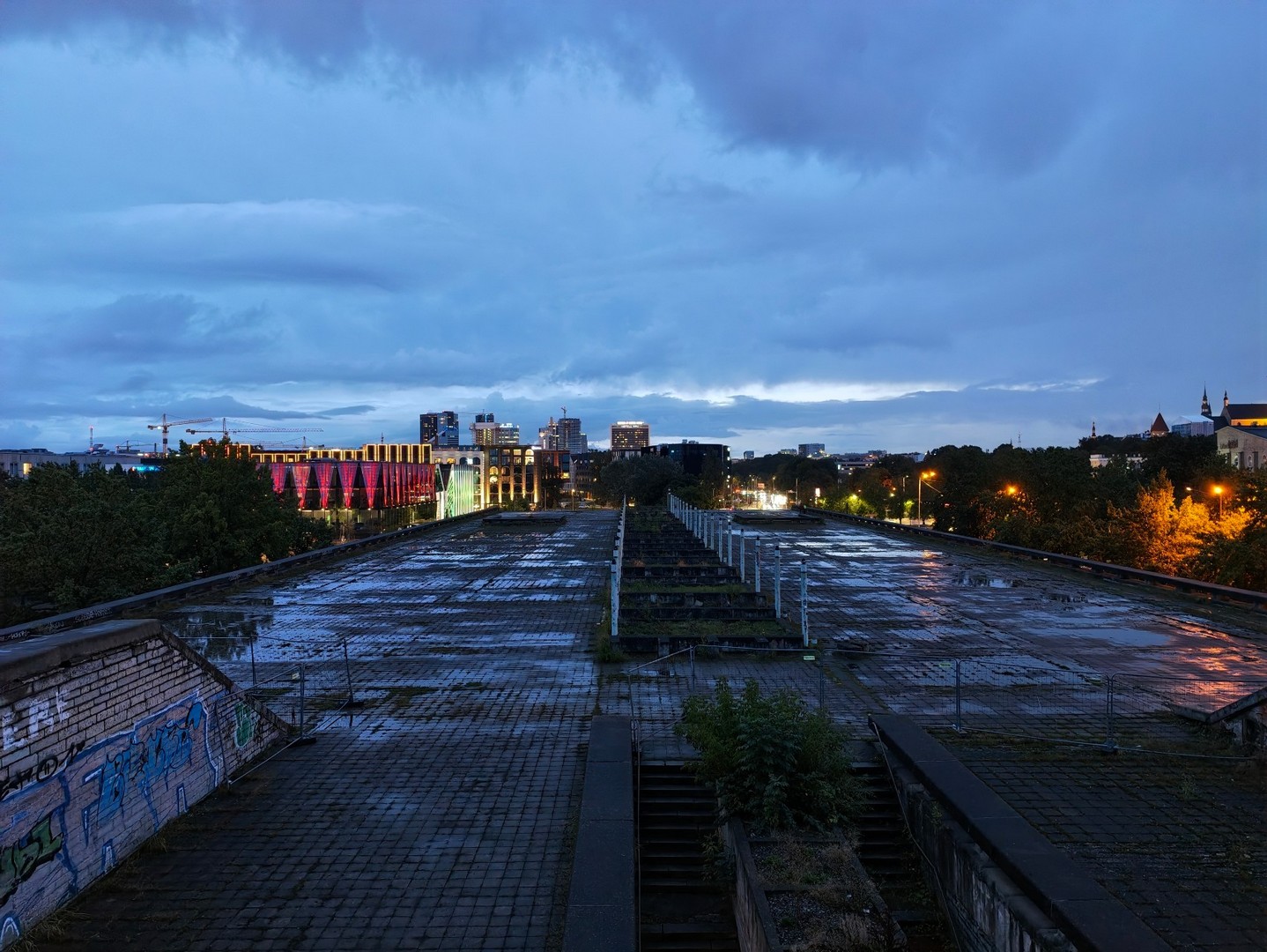 Wieczorny widok z Linnahall na oświetlony Tallinn i panoramę miasta po deszczu