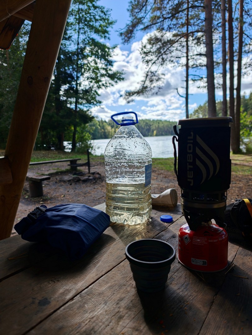 Jetboil, filtrowana woda i kubek na stole w wiacie biwakowej nad jeziorem Pikkjärv w Estonii 