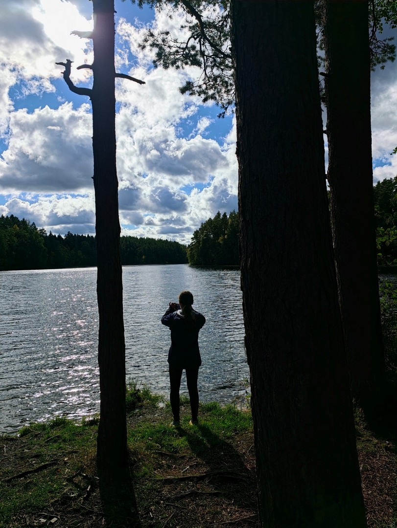 Sylwetka turystki stojącej nad brzegiem jeziora Pikkjärv podczas trekkingu w Estonii 