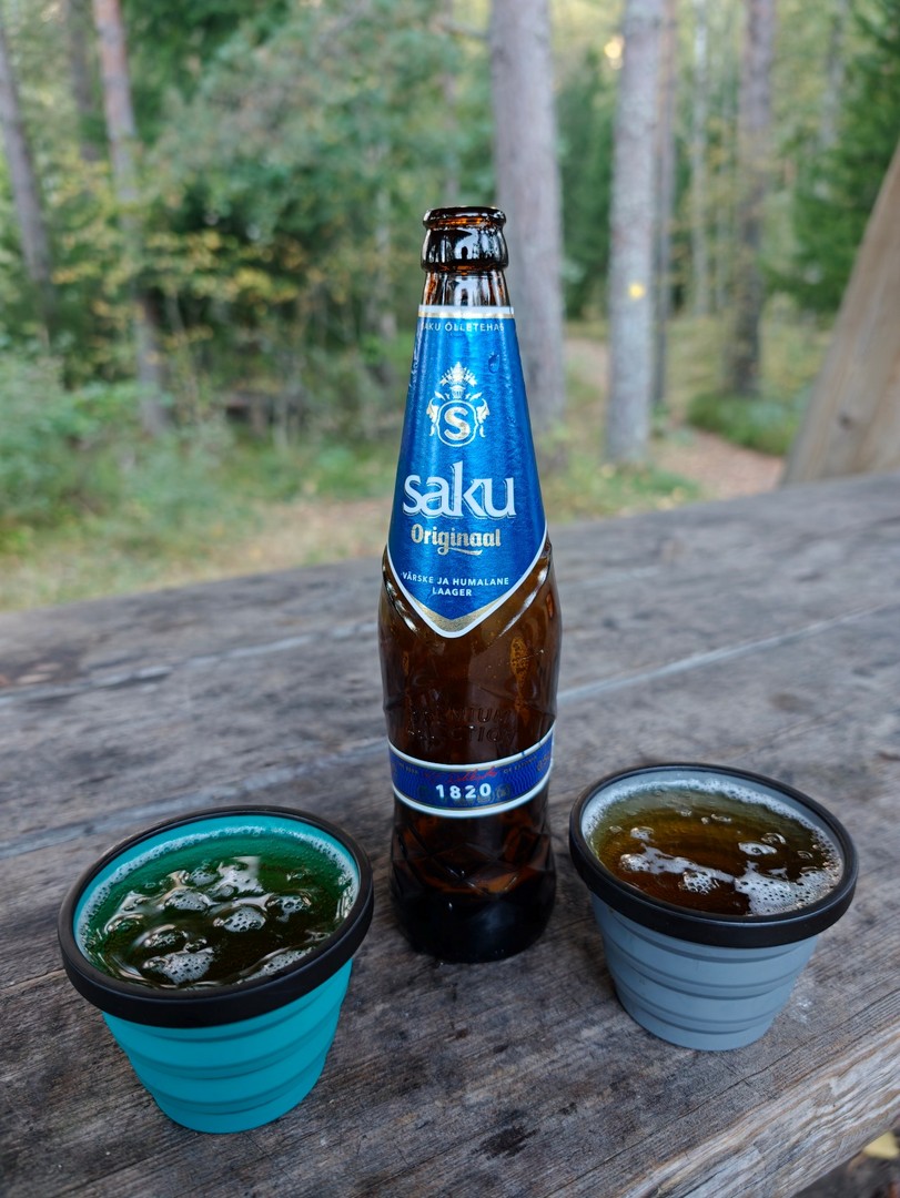 Butelka estońskiego Saku Original i dwa kubki na stole podczas biwaku na Jussi telkimisala